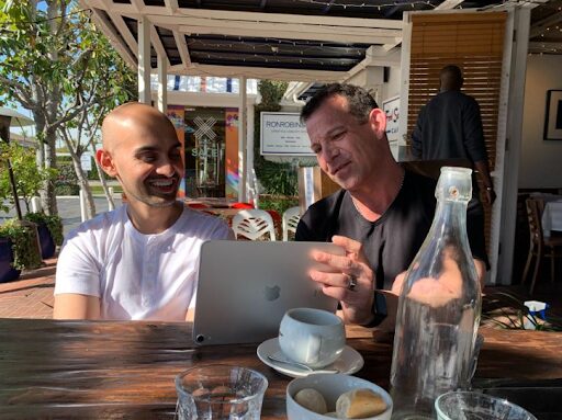 Rich Schefren and SEO consultant Neil Patel looking at a laptop at an outdoor cafe